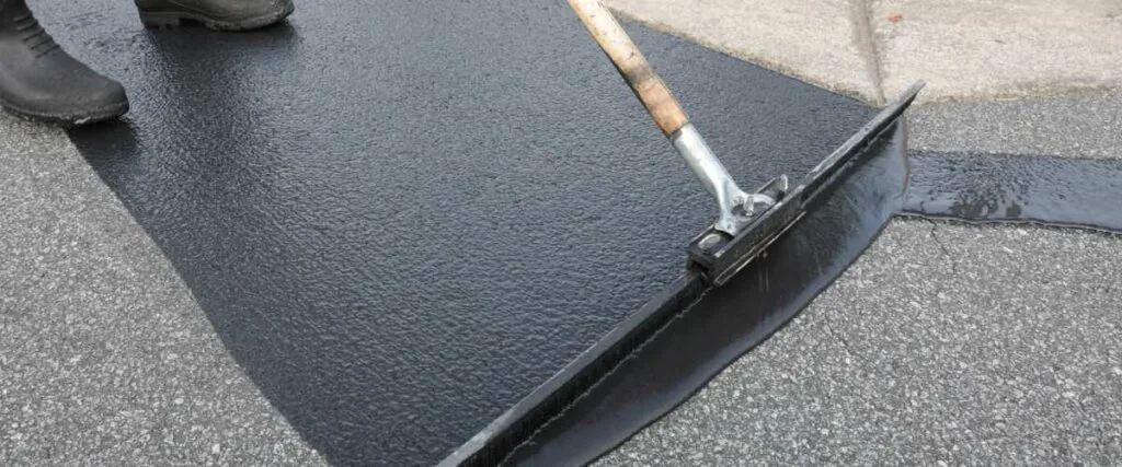 distributing sealcoat on asphalt