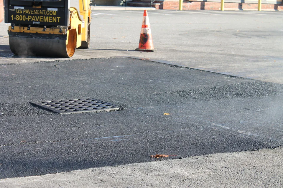 fresh asphalt patch around a storm drain