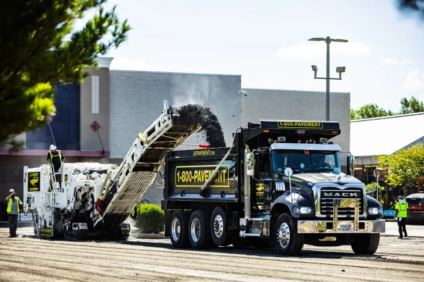 us pavement cold planer loading asphalt millings into a dump truck